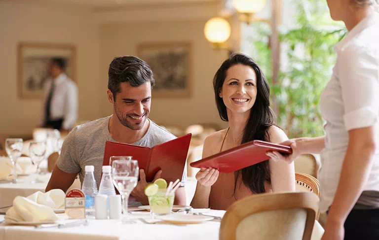 dwie osoby przy stole w restauracji przeglądające menu